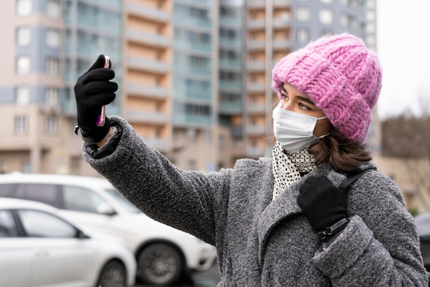 Woman with medical mask taking a selfie in the city