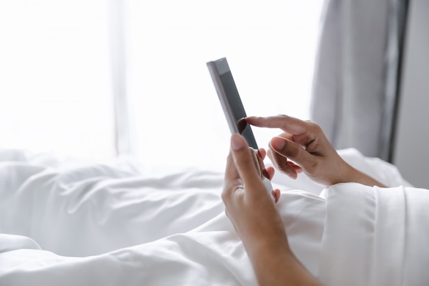 Woman with mobile phone on bed