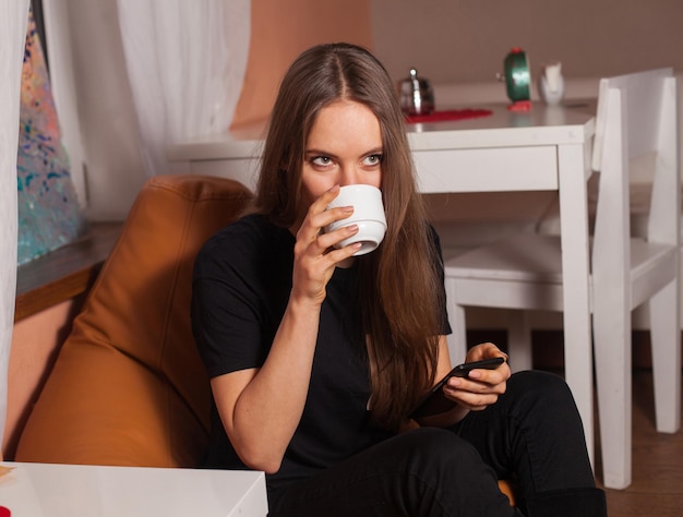 Woman with mobile phone and cup of coffee