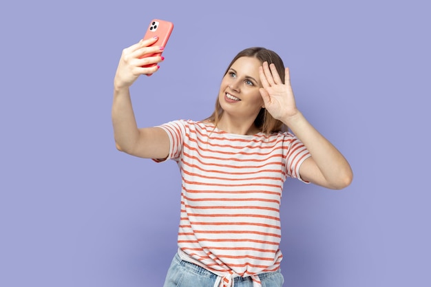 Woman with mobile phone phone and having video call having hi or bye with hand