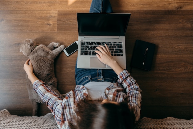 Woman with notebook, laptop and cat.