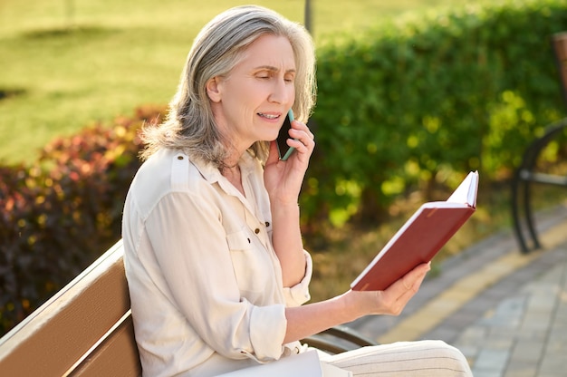 Woman with notebook talking on smartphone