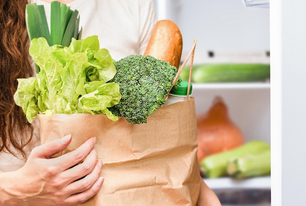 Woman with a package of fresh food by the refrigerator