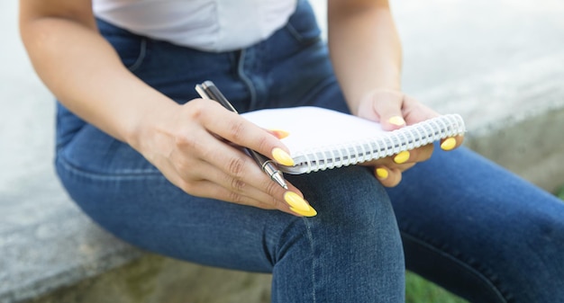 Woman with pen writing on notepad in the outdoors