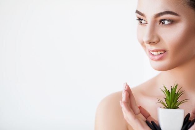 Woman with perfect skin holds a green plant in her hands