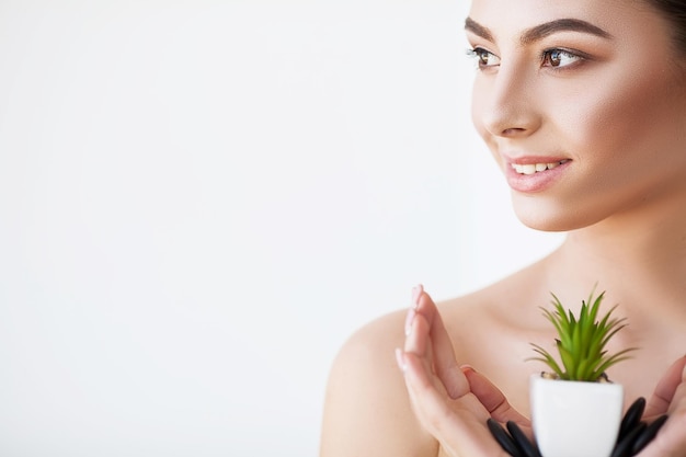 Woman with perfect skin holds a green plant in her hands