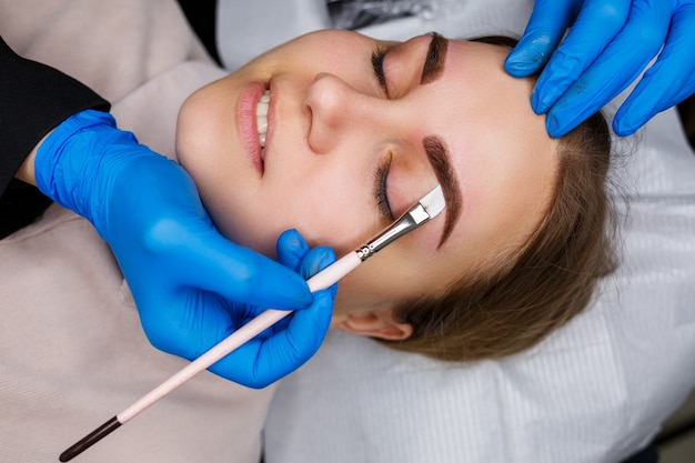 Woman with permanent makeup tattoo on her eyebrows. Close-up beautician makes a sketch of the eyebrows. Professional make-up and cosmetic skin care.