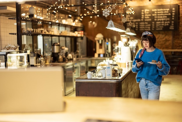 Woman with phone carrying her order at modern coffee shop