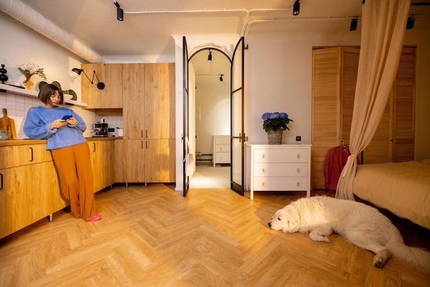 Woman with phone on kitchen of modern studio apartment