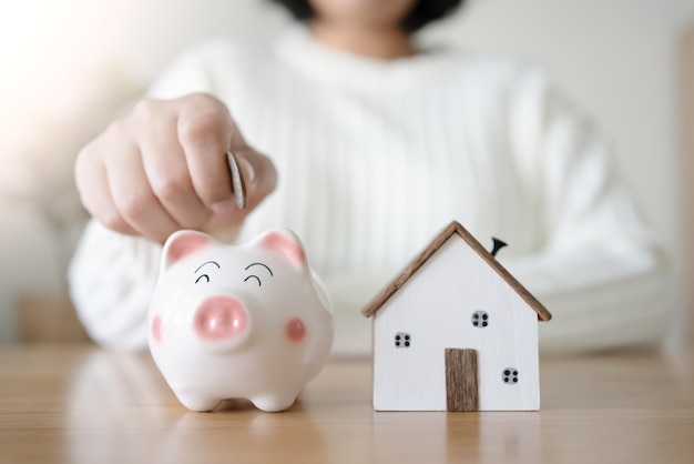 Woman with piggy bank and future house concept of saving