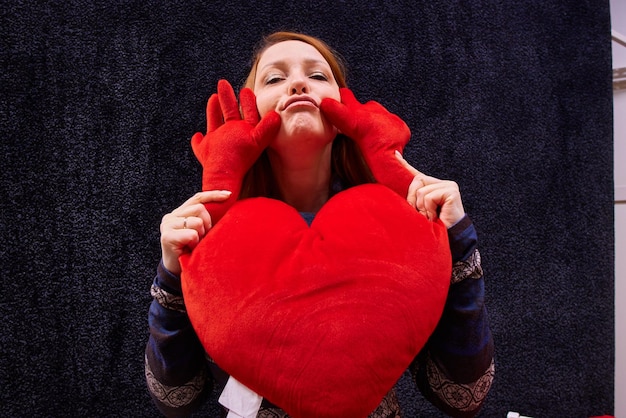 Photo a woman with a pillow in the form of a red heart for valentine's day