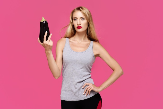 Woman with pink background with a beautiful smile holding an eggplant The concept of a healthy food