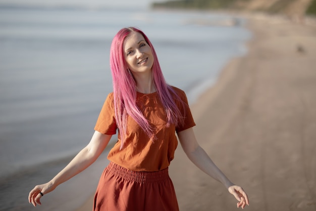 woman with pink hair enjoying the sun and wind on the beach