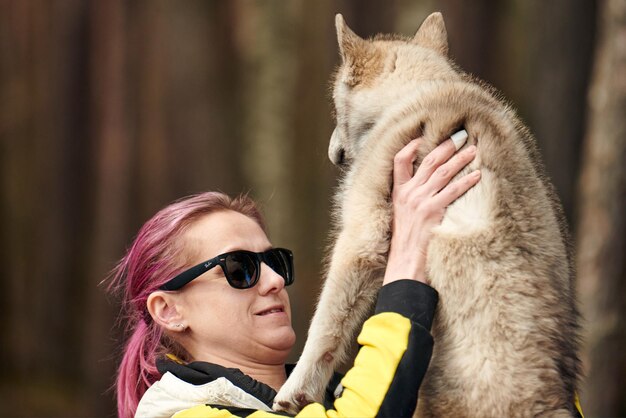 Woman with pink hair hugs beloved Siberian Husky puppy true love of human and pet