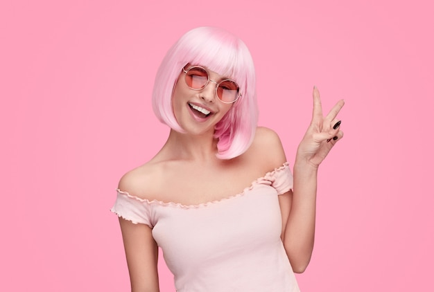 Woman with pink hair showing V sign