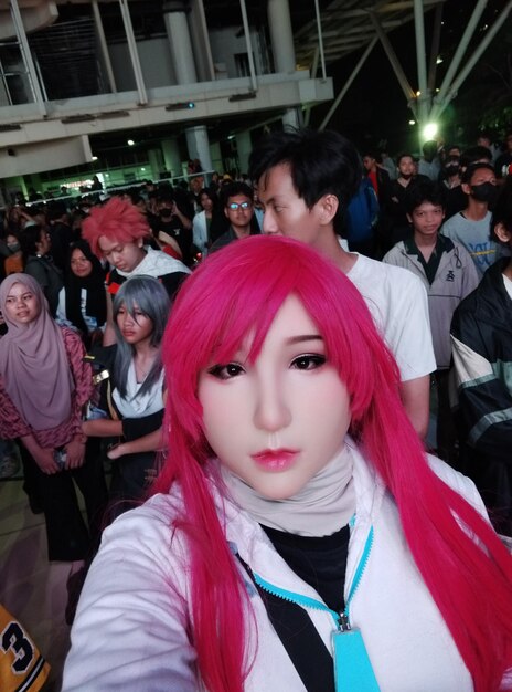 Photo a woman with pink hair and a white shirt has a blue ribbon around her neck