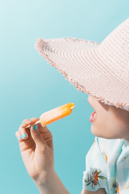 woman with a pink hat eating an orange ice cream