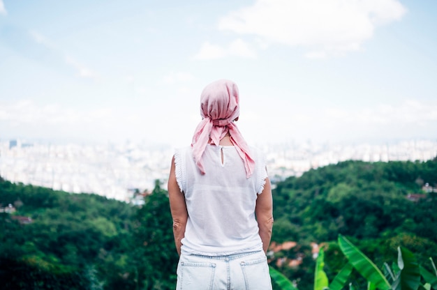 Woman with pink headscarf looking at the horizon. Cancer concept