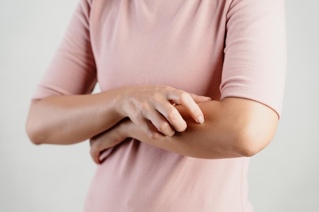 Photo a woman with a pink shirt is scratching her arm