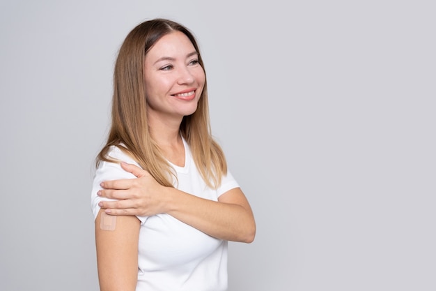 Woman  with a plaster on her hand rejoices from receiving a vaccination against coronavirus  Covid