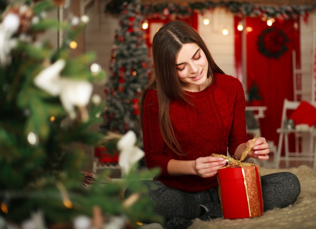 Woman with presents on scene of Christmas tree and new year decorations