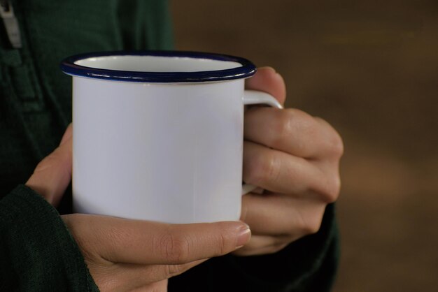 Woman with pretty hands holding a white mug drinking coffee or tea