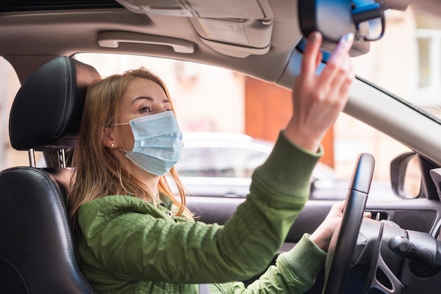 Woman with protection mask in her car