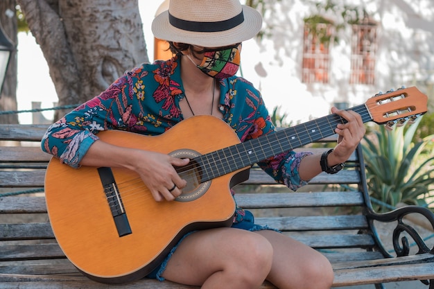 Woman with protective mask playing her acoustic guitar