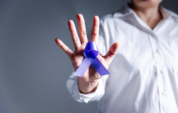 Woman with purple ribbon on palm background closeup with space for text Domestic violence awareness Purple Ribbon for supporting people living Healthcare and World cancer day concept