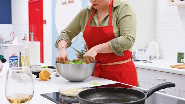 Woman with red apron cooking in a white kitchen