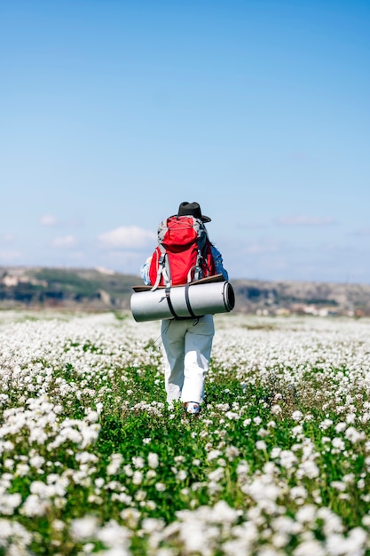 Woman with red backpack in flowery field