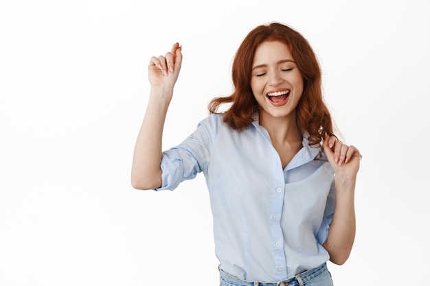 woman with red curly hair, having fun on free time, smiling carefree and happy, enjoying leisure, standing in blouse on white