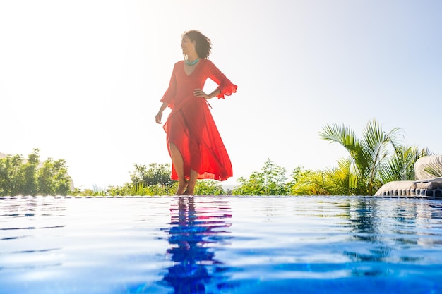 Woman with red dress next to an outdoor tropical pool