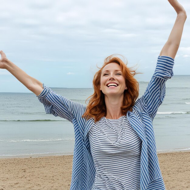 a woman with red hair is standing on a beach with her arms up in the air