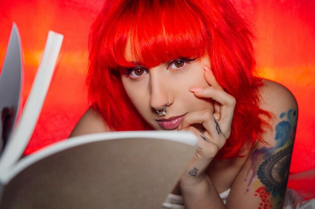 Woman with red hair and a nose piercing reading a book