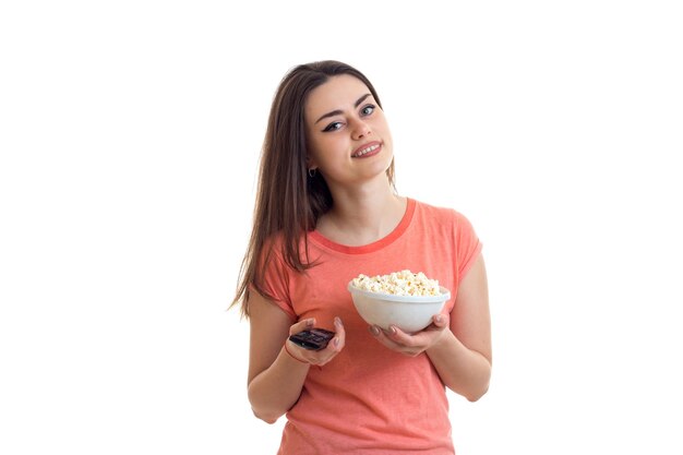 Woman with remote control from the tv and popcorn in the hands isolated on white