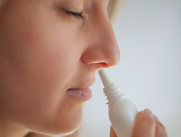 A woman with a runny nose holds a medicine in her hand