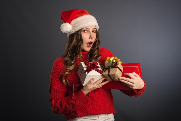 Woman with Santa hat holding Christmas gifts