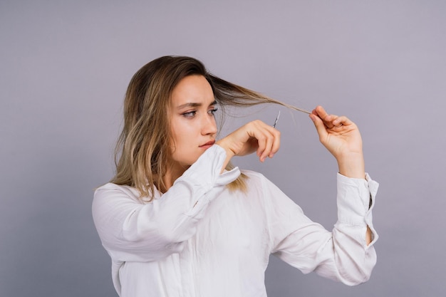 Woman with scissors having hair cut Amazed female with straight hair scissor Haircare concept