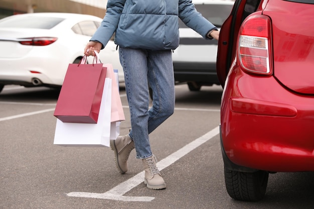 Woman with shopping bags near her car outdoors closeup