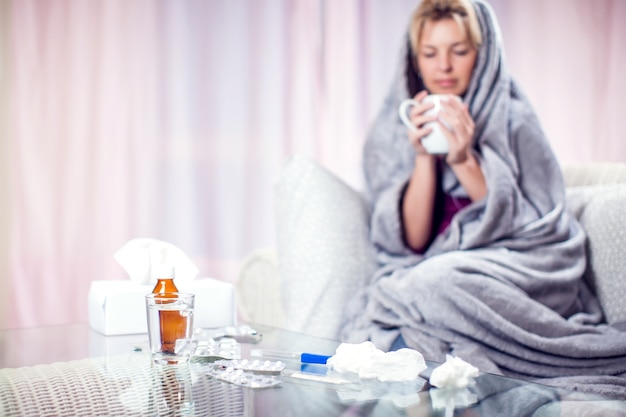 Woman with short blond hair got the flu and drinking hot tea at home. People, healthcare and medicine concept