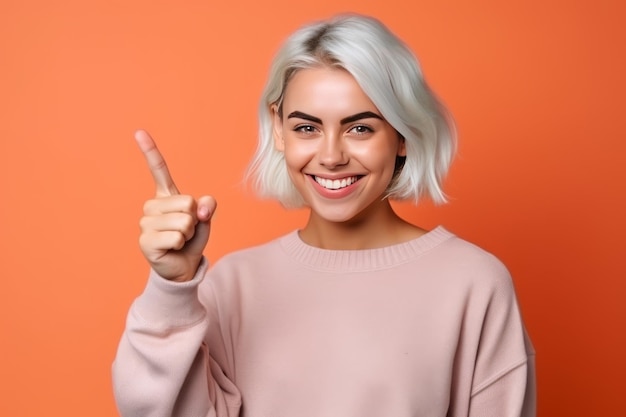 A woman with short blonde hair and a pink sweater points up with her index finger.