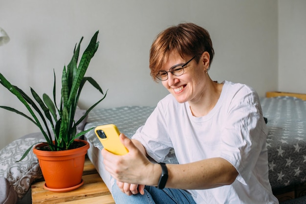 Woman with short hair at home sitting on the floor with her smartphone