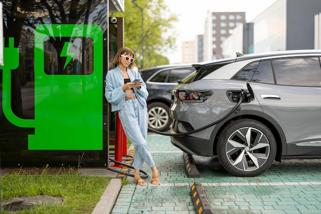 Woman with a smart phone waiting for her electric car to charge