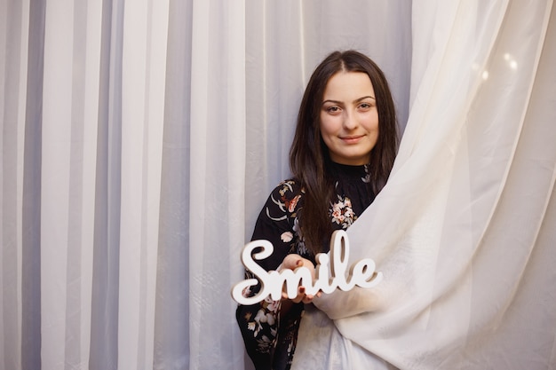 Woman with a smile wooden sign. Happiness concept.