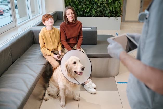 Woman with son and with their dog have a consultation with the vet at clinic