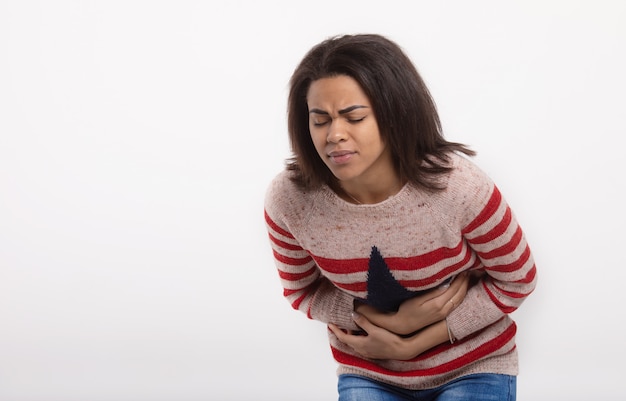 woman with stomach abdomen pain having bad aches isolated on white wall. Face expression