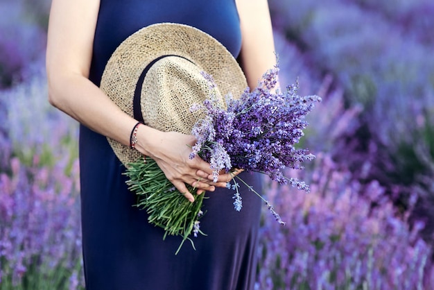 woman with straw hat and lavender bouquet in her hands in lavender field in summer.