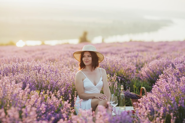 Woman with straw hat sitting on the picnic in lavender field