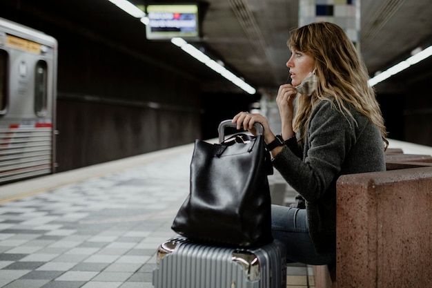 Woman with a suitcase waiting for the train during the coronavirus pandemic